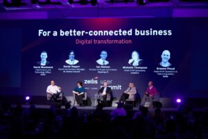 The stage at the Zellis User Summit 2024 Digital transformation panel. 5 people sit on stage ion front of a screen detailing their names and job titles; David Woodward, Chief Product and Technology Officer, Zellis. Sarah Hopper, Payroll and Pensions Manager, St. Helens Council. Ian Hodson, Director of People and Culture, Housing 21. Michell Thompson, Head of HR Operations, Lookers. Graeme Proud, Head of HR Operations & talent Acquisition, Zellis.