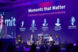 photograph from Zellis User Summit. 5 people sit on a stage with the screen behind titled 'Moments that Matter. Employee engagement and wellbeing' The screen shows a headshot, name and job title for each person: Caroline Drake, Chief People Officer, Zellis. Katie Duxbury, Head of Pay and Reward Services, Bupa. Sophie Baker, Head of Payroll, Harrods. Emily Trant, Chief Impact Officer, Wagestream. Anita Lettink, Analyst and Author.