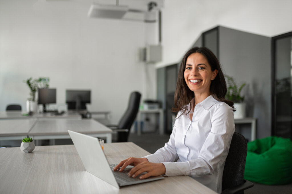 [decorative] professional woman smiles while using a laptop.