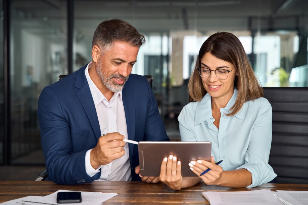 Decorative image. two professionals look at a tablet at tax year end.