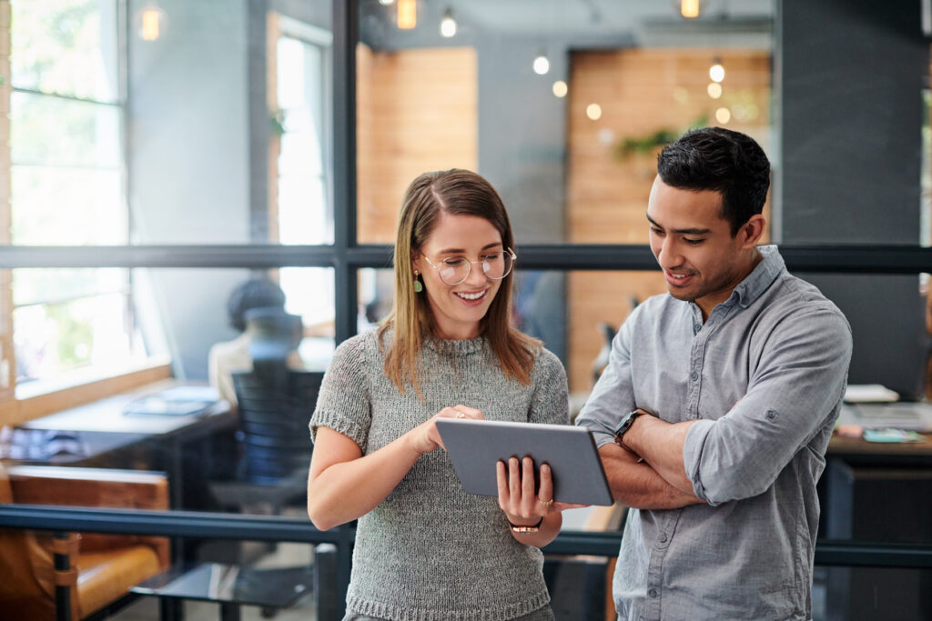 Decorative image. Two professionals discuss ai in payroll looking at a tablet computer.